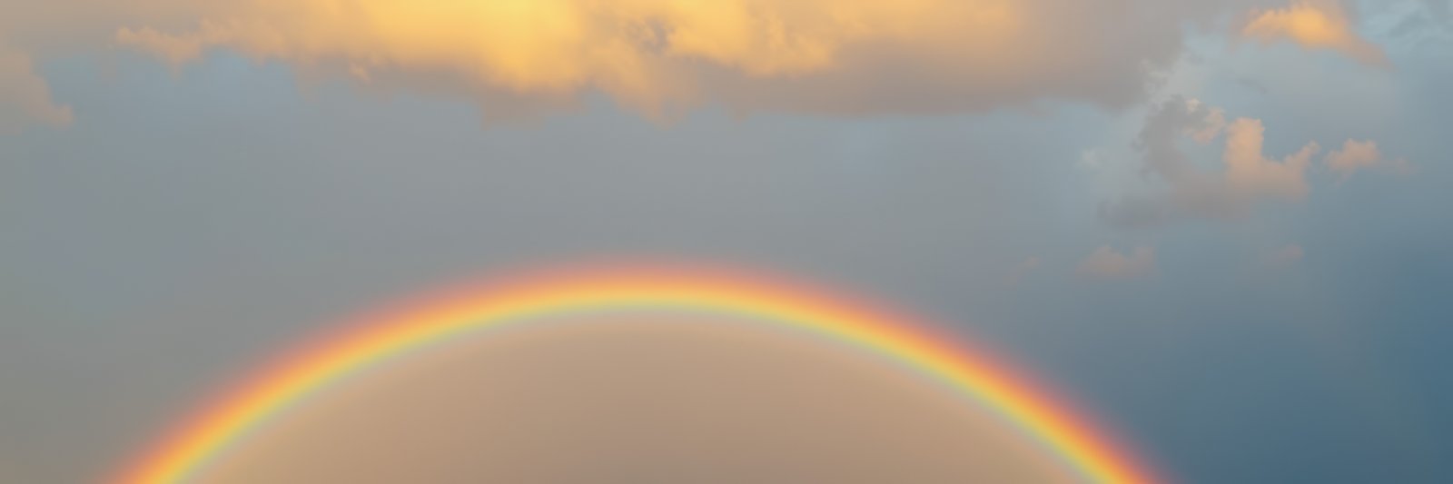 A partial rainbow is visible in the sky, its colorful arc spanning from one side of the frame to the other
